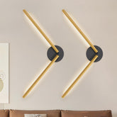 Two gold wall sconces on a beige wall with a couch in the foreground.